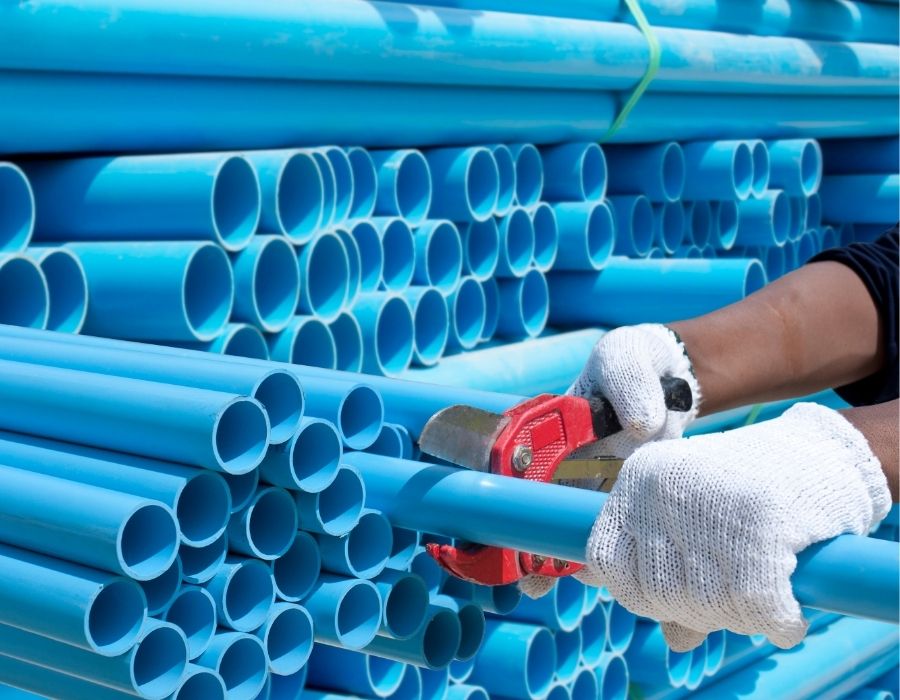 blue-pvc-pipe Plumber cutting blue PVC pipe for plumbing installation using pipe cutter tool