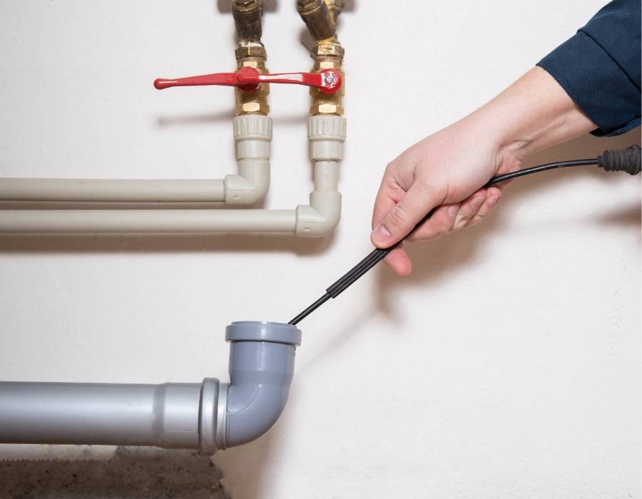 pro-master-services-drain-cleaning-services-in-davis-county-utah Plumber using drain snake to unclog residential plumbing pipe during professional drain cleaning service