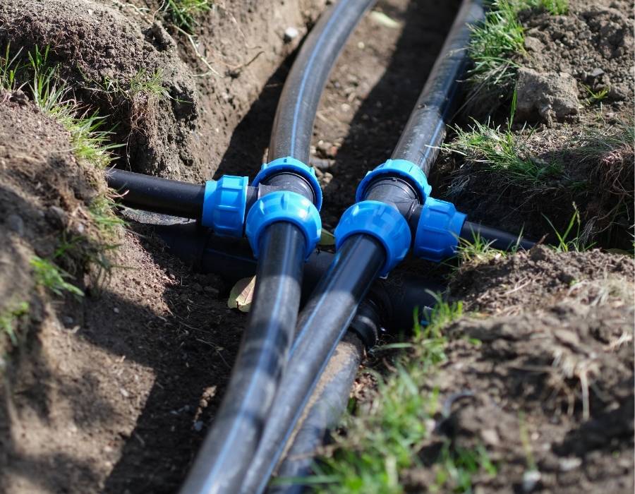 New underground water line installation with black polyethylene pipes and compression fittings for residential plumbing system