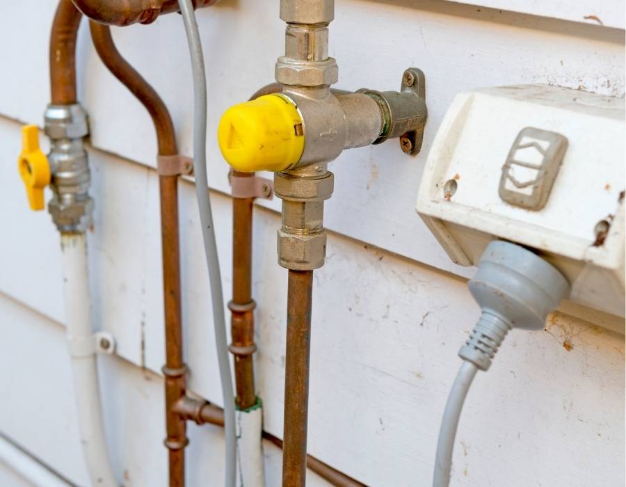 pro-master-services-plumbing-and-drain-service-in-weber-county Outdoor residential gas line and plumbing valve system connected to utility service wall