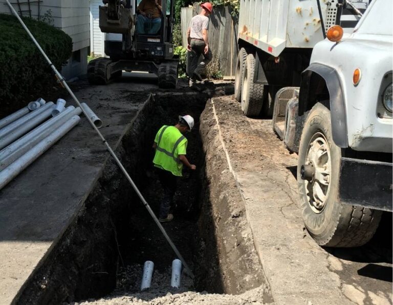 Pro Master Services crew performing trench excavation for sewer line replacement at residential property using heavy equipment