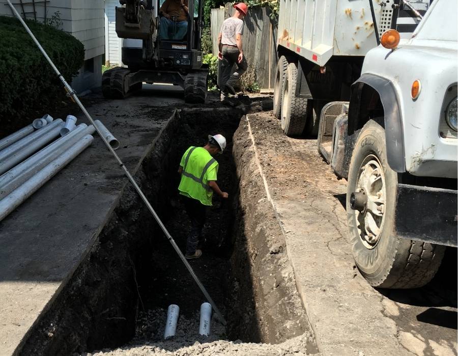 Pro Master Services crew performing trench excavation for sewer line replacement at residential property using heavy equipment