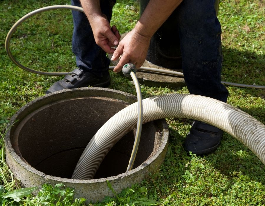Plumber performing sewer line inspection and cleaning using hose equipment at residential property