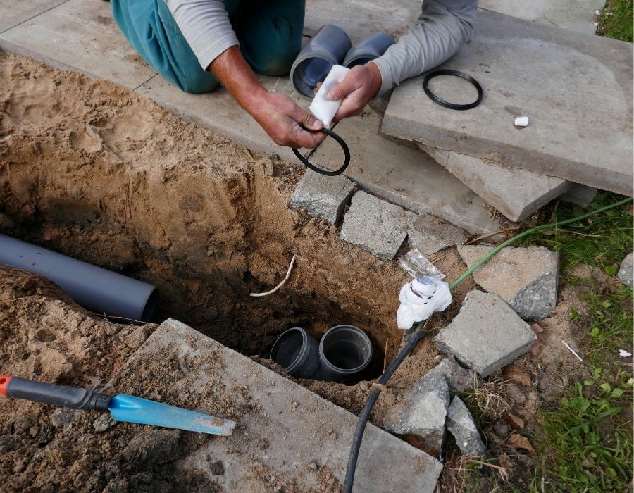 Plumber preparing sewer line connection during underground pipe repair and installation