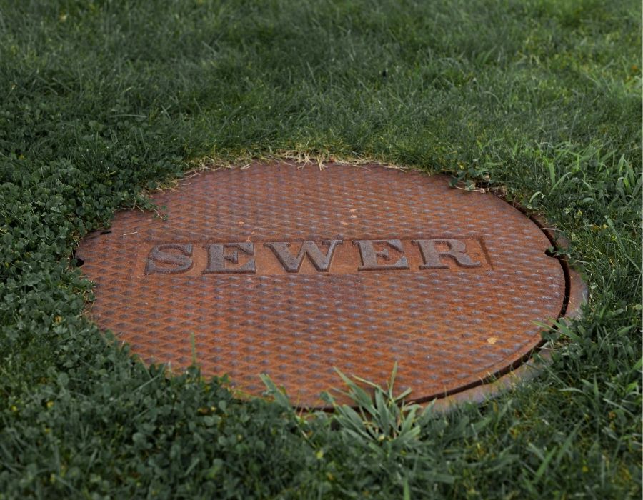 Sewer manhole cover on residential lawn for underground sewer line access