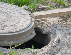 Partially opened sewer access point on residential property with exposed concrete lid