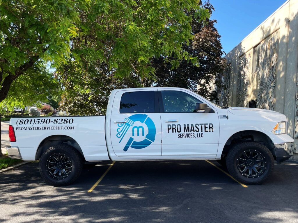 pro-master-services-truck White Pro Master Services LLC work truck with company logo, phone number, and website parked under a tree in a sunny parking lot in Utah.