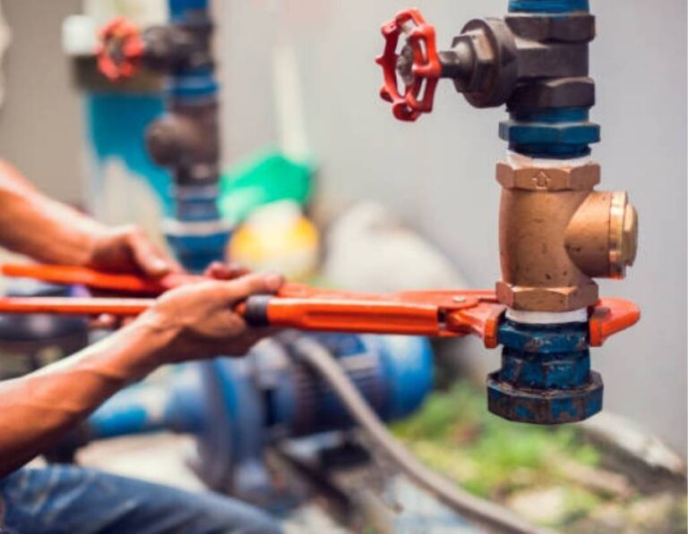 Emergency plumber in Taylorsville, UT using a pipe wrench to repair industrial water valve connection