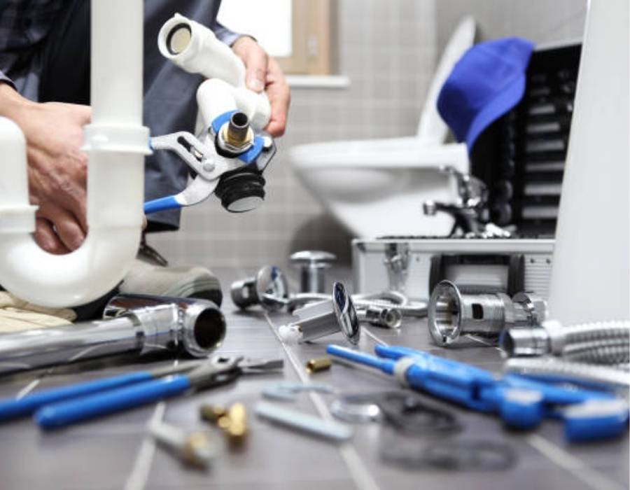 Professional plumber repairing bathroom sink drain with tools spread across the floor – Sandy, UT plumbing services