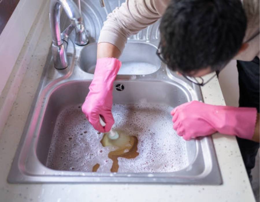 Homeowner dealing with clogged kitchen sink drain full of dirty water – Pro Master Services Bountiful, UT plumbing
