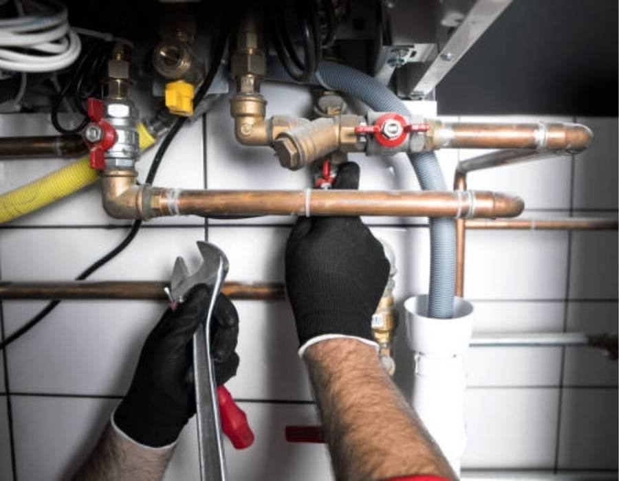 Emergency plumber in Taylorsville, UT repairing copper water pipes with wrench under sink – Pro Master Services