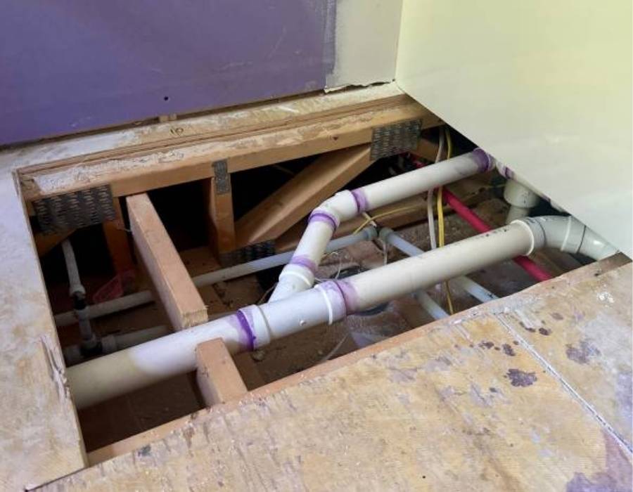 Exposed PVC plumbing pipes under bathroom floor during repair – Pro Master Services plumbing in Sandy, UT homes