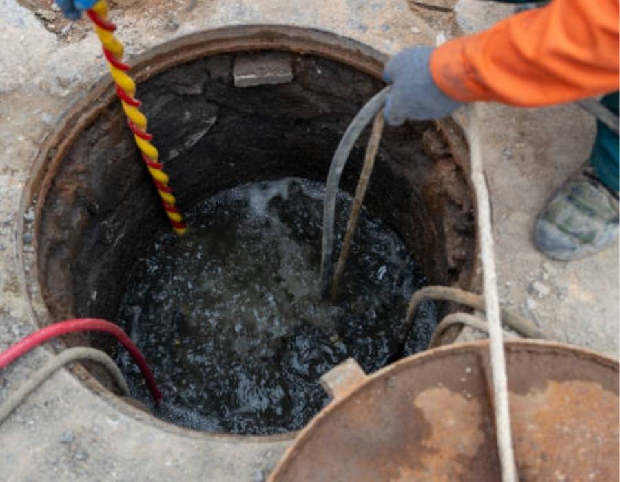 Pro Master Services plumber performing sewer line inspection and cleaning for businesses using high-pressure hoses